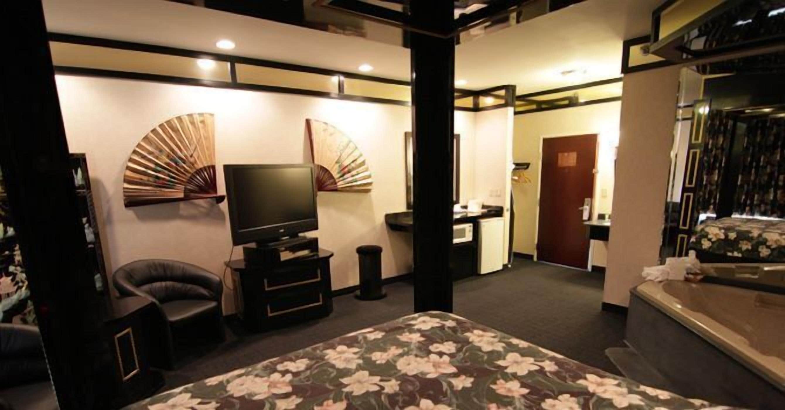 Habitación de hotel con cama, televisor, escritorio, silla y baño.