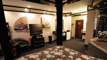 Habitación de hotel con cama, televisor, escritorio, silla y baño.