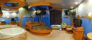 A room with a large bed, a bathtub, and a television. - Magnolia Inn And Suites (Southaven)
