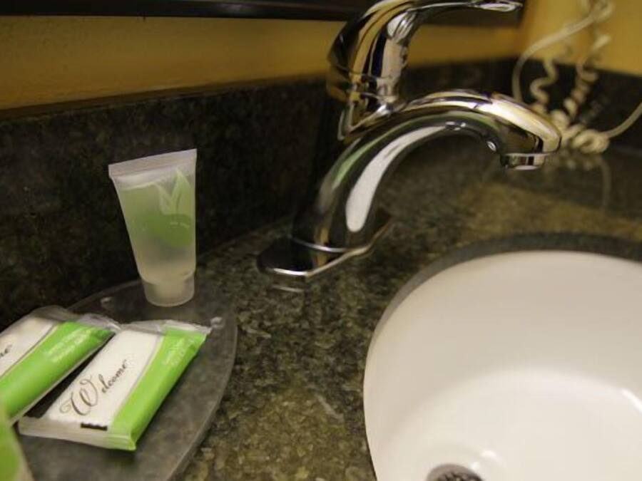 Un lavamanos con grifo cromado, un lavabo blanco y un paquete de artículos de tocador verde y blanco sobre la encimera.