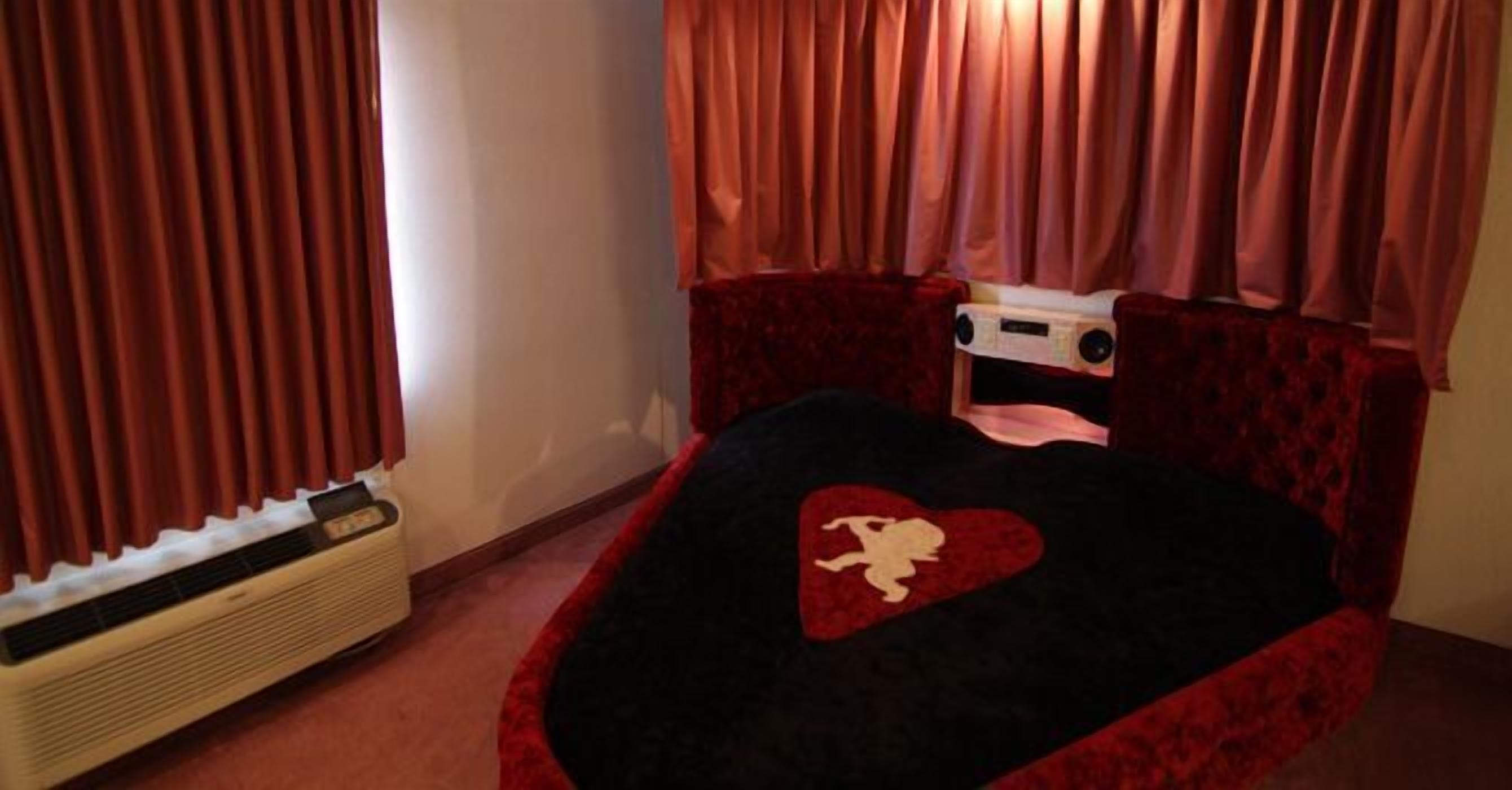 A bedroom with a bed, a heater, and curtains.