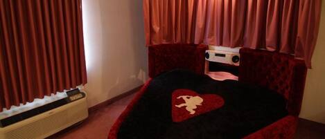 A bedroom with a bed, a heater, and curtains.