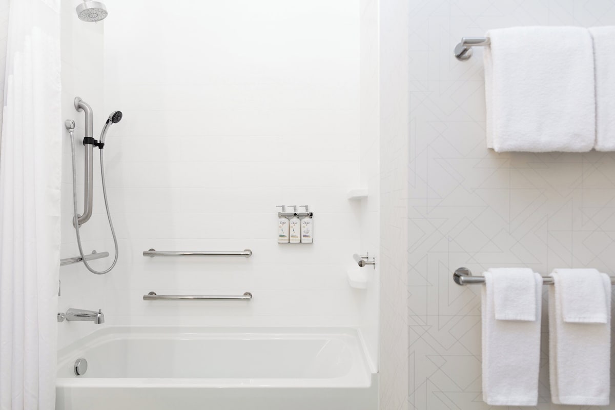 Un baño moderno con bañera, ducha y barras de apoyo.