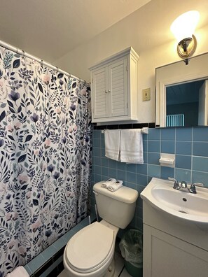 Un baño con inodoro, lavamanos y cortina de ducha con estampado floral.
