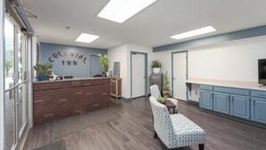 A modern kitchen with a brick island, blue cabinets, and a seating area with patterned chairs. - Colonial Inn (Camden)