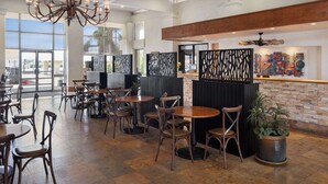 A spacious restaurant with high ceilings, a chandelier, and a view of the outdoors. - Ramada by Wyndham Tucson (Tucson)
