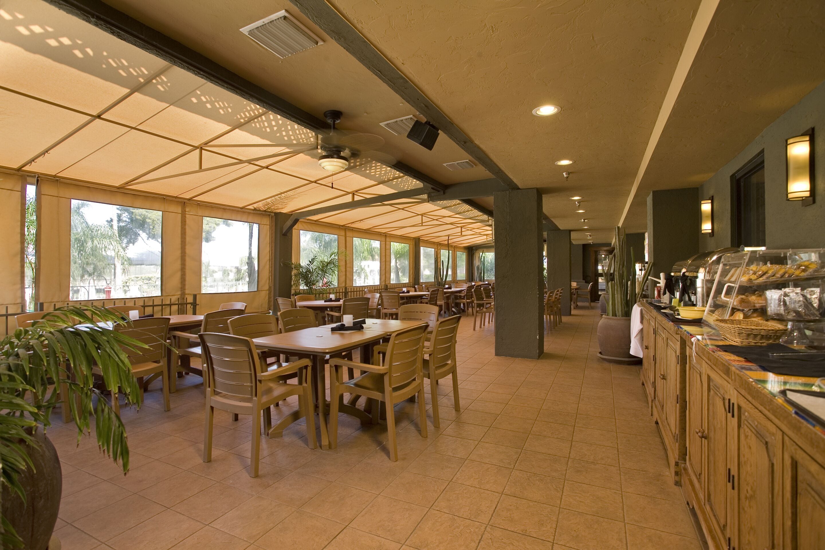 Una cafetería amplia con techos altos, ventanas grandes y diversas opciones de asientos.