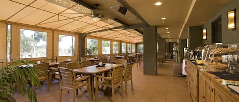 Una cafetería amplia con techos altos, ventanas grandes y diversas opciones de asientos.