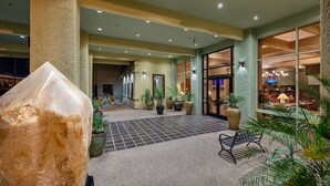 A spacious lobby with a large rock centerpiece, tiled flooring, and potted plants. - Ramada by Wyndham Tucson (Tucson)