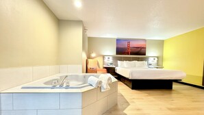 Una habitación de hotel moderna con una bañera grande, una cama y un escritorio con una silla.