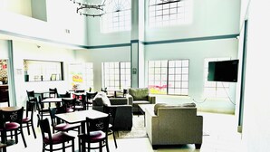 A spacious dining area with multiple tables and chairs, a sofa, and a television. - Quality Inn near SeaWorld - Lackland (San Antonio)