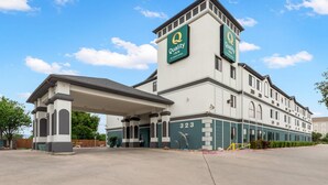 A Quality Inn hotel with a prominent tower, a covered entrance, and a clear sky. - Quality Inn near SeaWorld - Lackland (San Antonio)