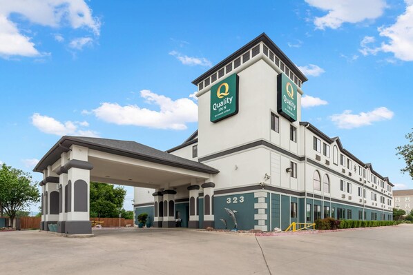 A Quality Inn hotel with a prominent tower, a covered entrance, and a clear sky. - Quality Inn near SeaWorld - Lackland (San Antonio)