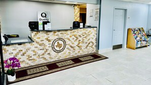 A reception area with a mosaic wall, a reception desk, a coffee machine, and a display of postcards. - Quality Inn near SeaWorld - Lackland (San Antonio)