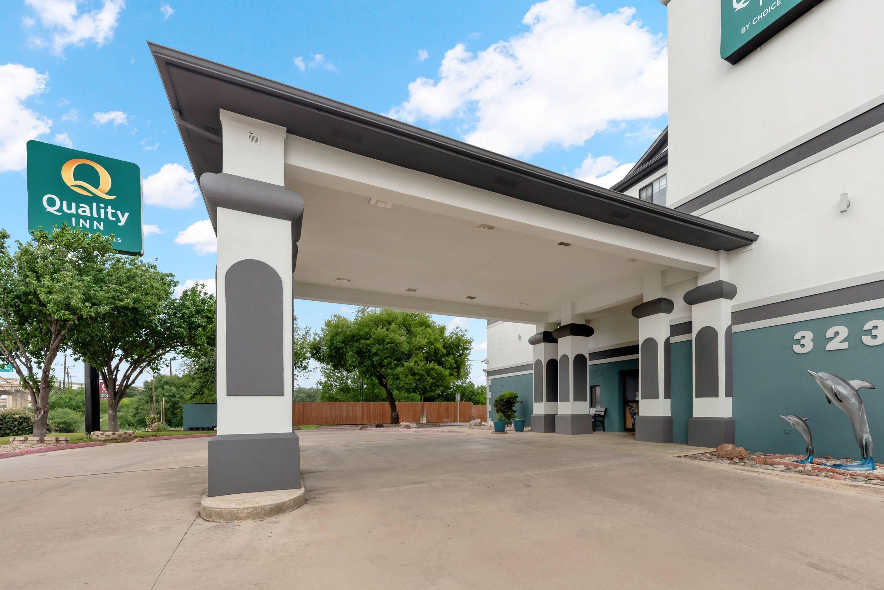 A hotel entrance with a covered walkway, a sign for Quality Inn, and a building number 323.