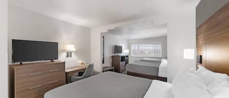 A hotel room with a bed, a desk, a television, and a window.