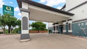 A hotel entrance with a covered walkway, a sign for Quality Inn, and a building number 323. - Quality Inn near SeaWorld - Lackland (San Antonio)