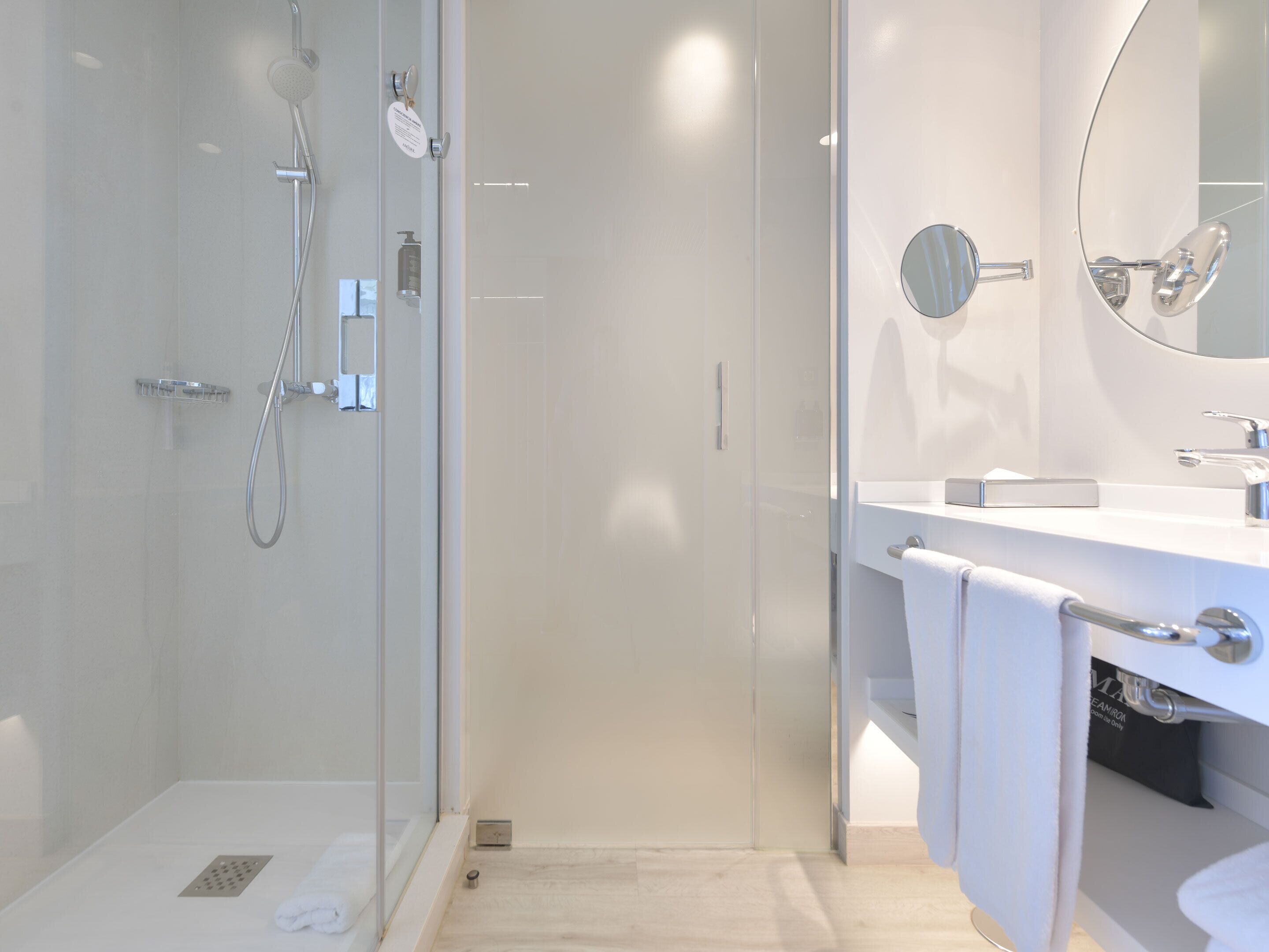 A modern bathroom with a glass shower enclosure, a white sink with a mirror, and a towel rack.