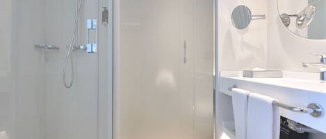 A modern bathroom with a glass shower enclosure, a white sink with a mirror, and a towel rack.