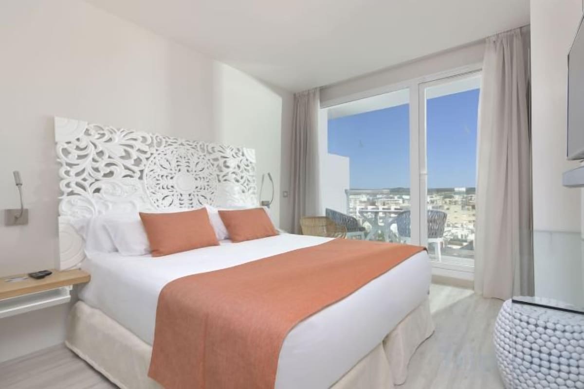 Ein Hotelzimmer mit großem Bett, Blick auf die Stadt und modernem Design.