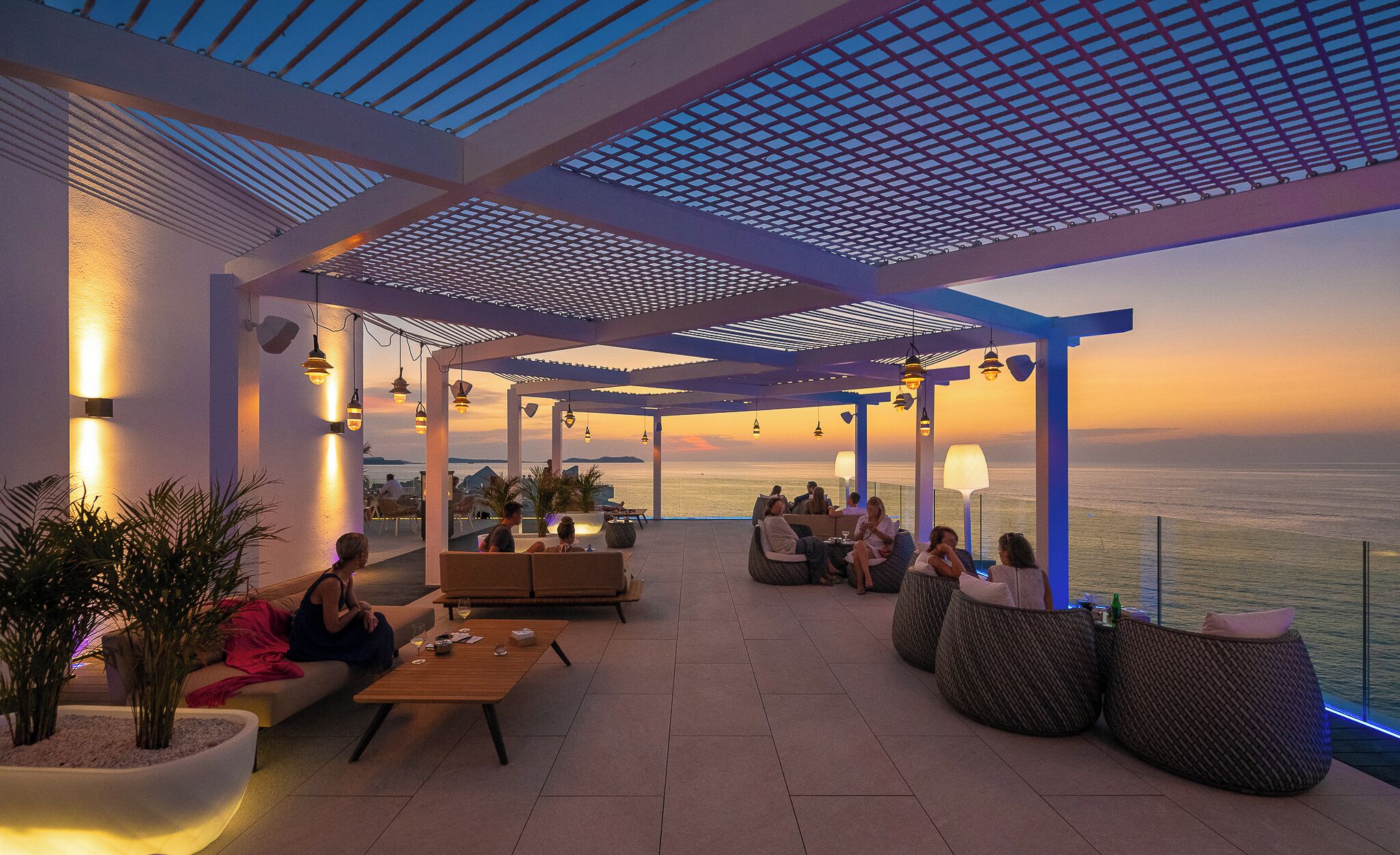 Un área de estar al aire libre con vistas al mar, que incluye una pérgola, sillones reclinables y mesas.