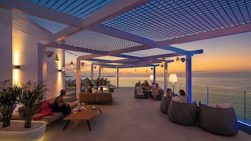 Un área de estar al aire libre con vistas al mar, que incluye una pérgola, sillones reclinables y mesas.