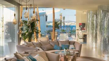 A modern living room with a large sofa, a glass coffee table, and hanging light fixtures.