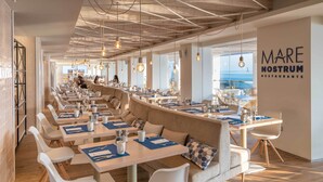A modern restaurant with a long counter, white chairs, and a view of the sea. - Amàre Beach Hotel Ibiza - Adults Recommended (Sant Josep de sa Talaia)