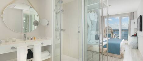 A modern bathroom with a glass-enclosed shower, a round mirror, and a vanity with a sink and towel rack.