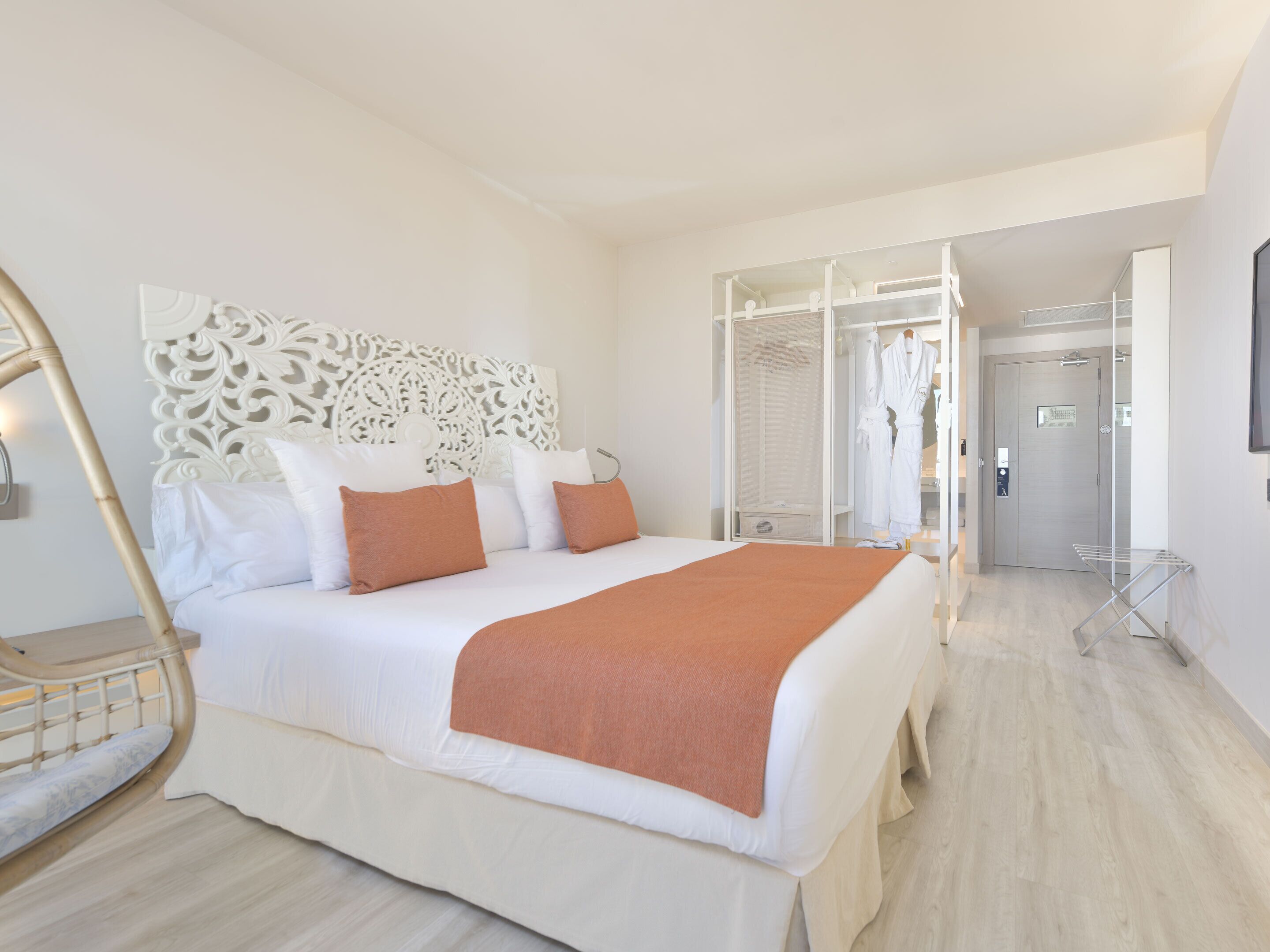 Une chambre d’hôtel moderne dotée d’un grand lit, d’une tête de lit décorative, d’un dressing et d’un espace douche.
