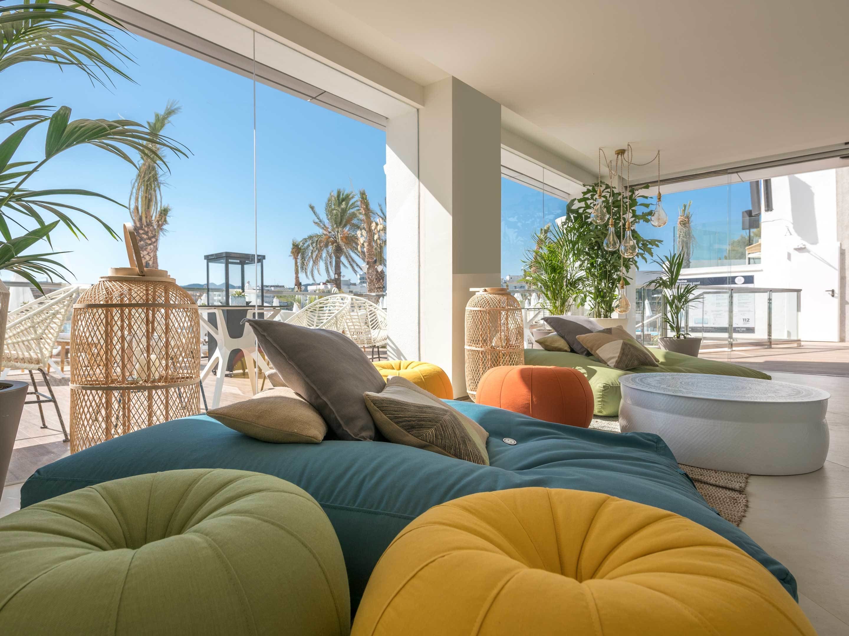 A modern outdoor seating area with colorful cushions, wicker furniture, and potted plants.