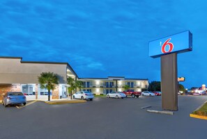 A motel with a prominent '6' sign, multiple parking spaces, and a modern building facade. - Motel 6 McDonough, GA (McDonough)