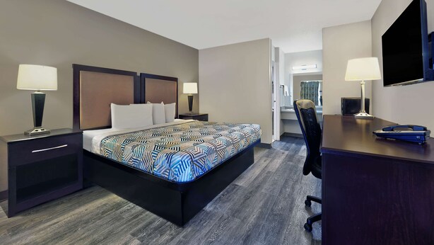 Una habitación de hotel con cama, mesitas de noche, escritorio, silla y televisión.