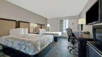 A hotel room with two beds, a desk, a chair, a television, and a window with curtains.