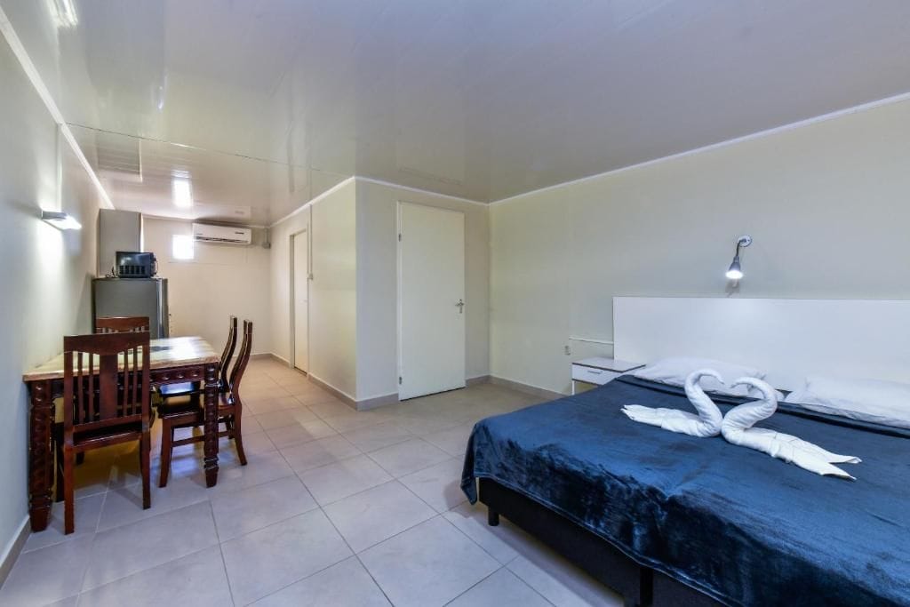 Una habitación de hotel con cama, escritorio, sillas y armario.