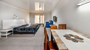 Een kamer met twee bedden, een bureau, een stoel, een televisie en een raam met gordijnen.