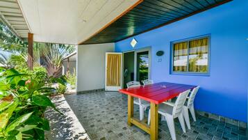 A covered patio area with a red table and white chairs, a blue wall, and a tiled floor.