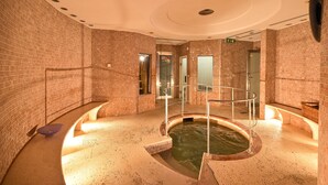 Un área de spa con un jacuzzi, barandilla de cristal y pared de ladrillo.