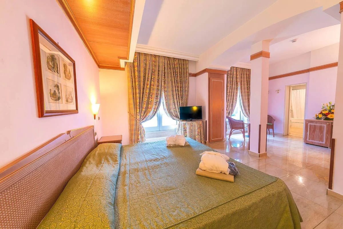 Una camera d'albergo con un letto, una televisione, una scrivania e una sedia.