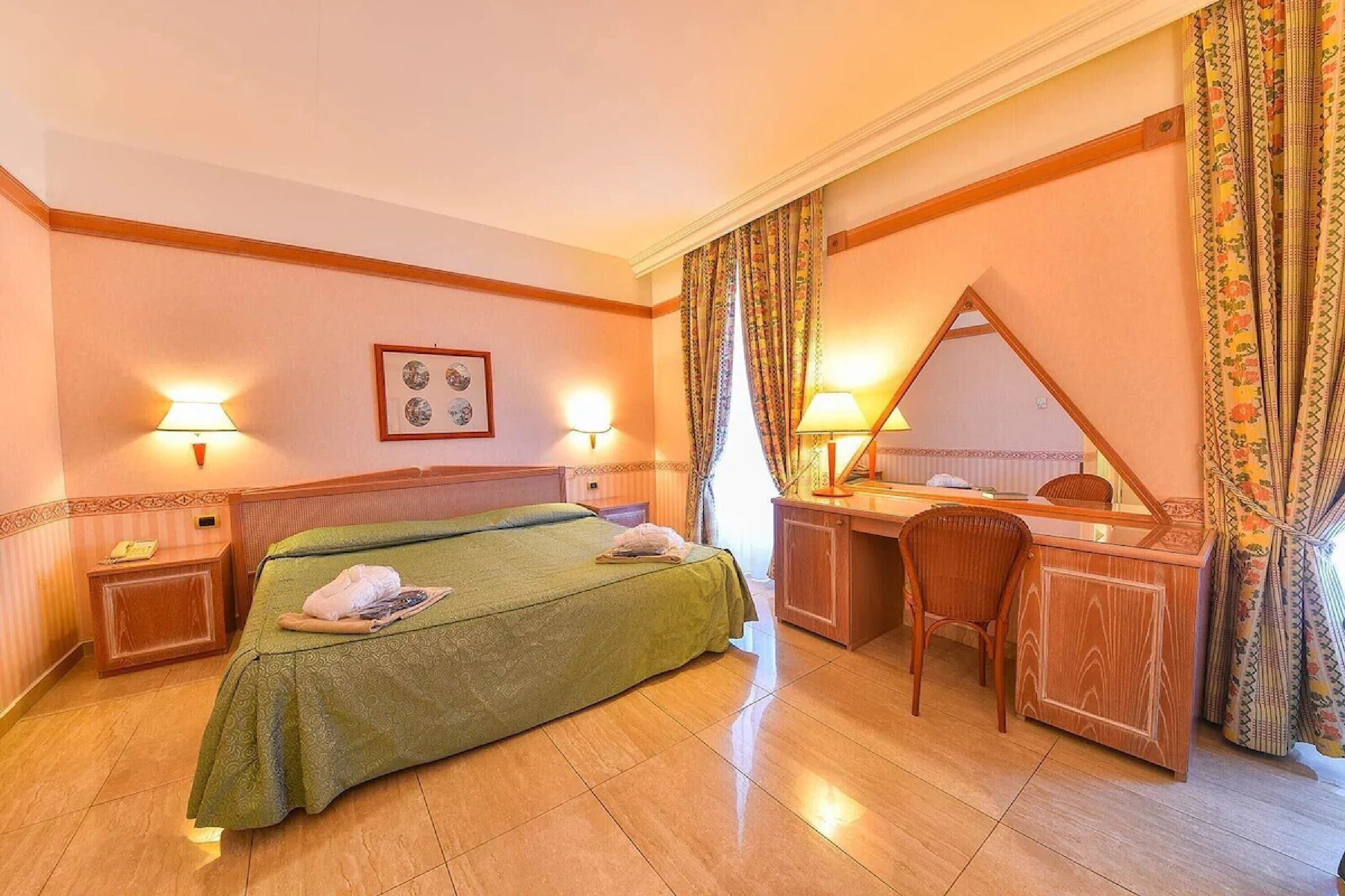 Une chambre d’hôtel avec un lit, un bureau, une chaise et un miroir.