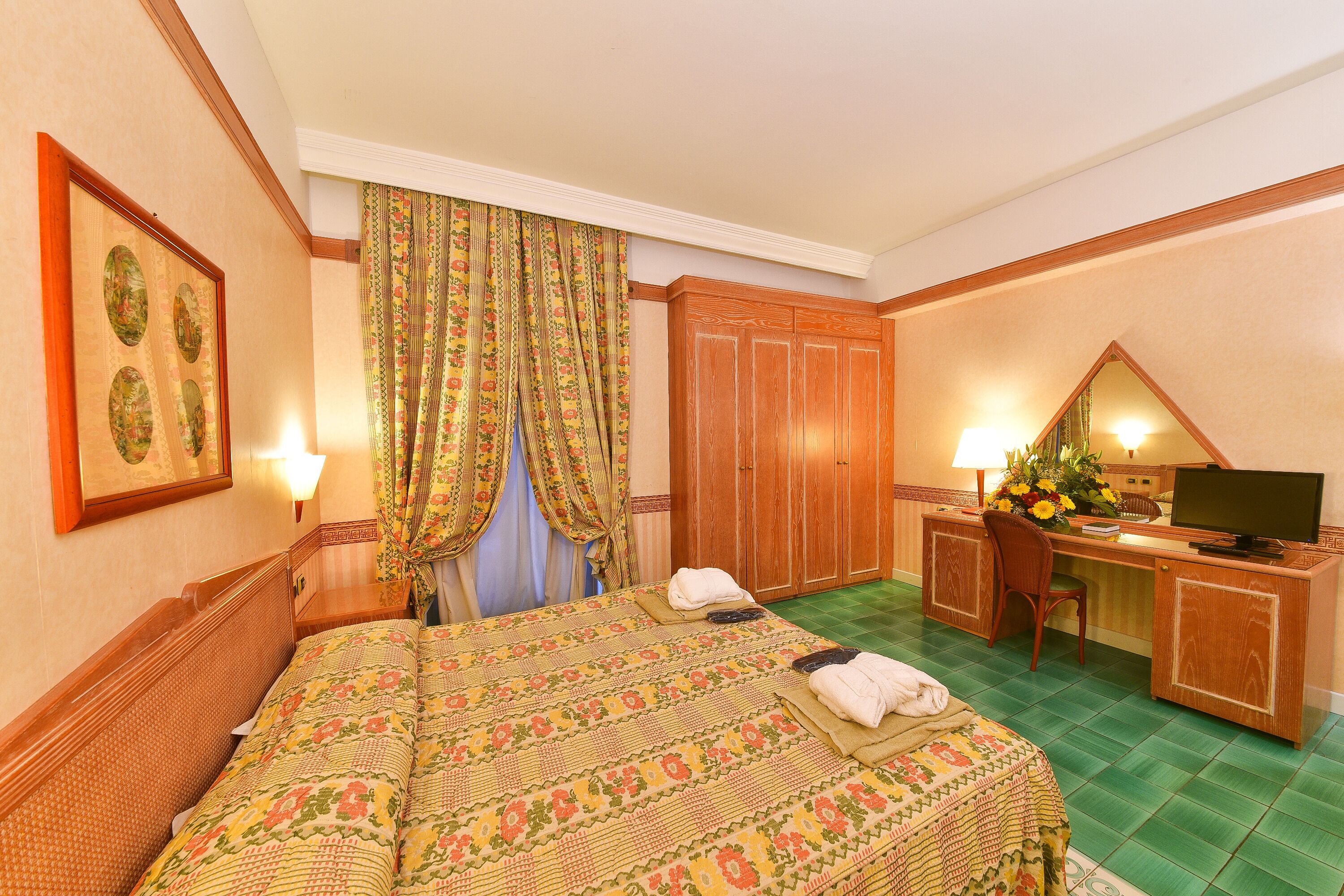 A hotel room with a bed, desk, chair, and a television.