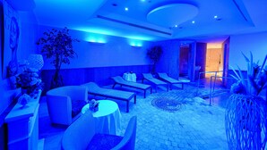 Un espacio interior con iluminación azulada, sillones, mesas y un suelo estampado.