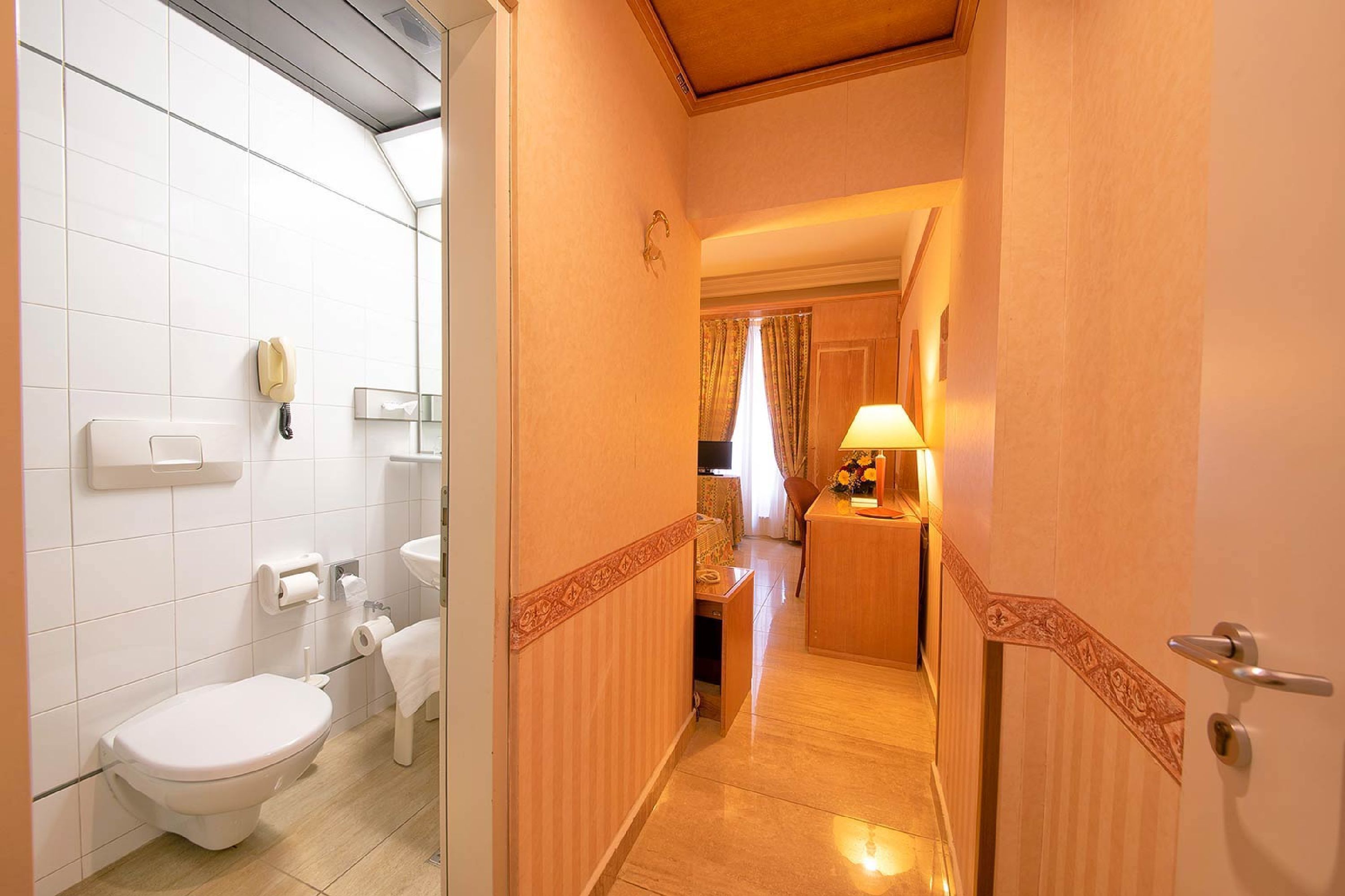 Une salle de bain d’hôtel équipée de toilettes, d’un lavabo et d’un téléphone.