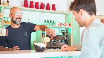 A bar area with a counter, shelves with bottles, and red mugs.