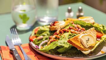 A plate of salad with various toppings, a fork, and a knife on a table with a placemat.