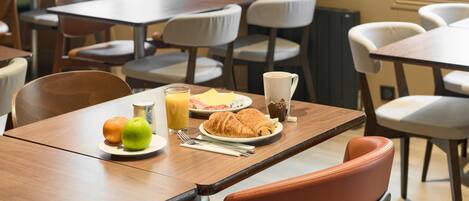 A dining area with tables and chairs, a plate with food, a glass of orange juice, and a bottle of milk.