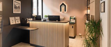 A reception desk with a modern design, a computer, and a plant.