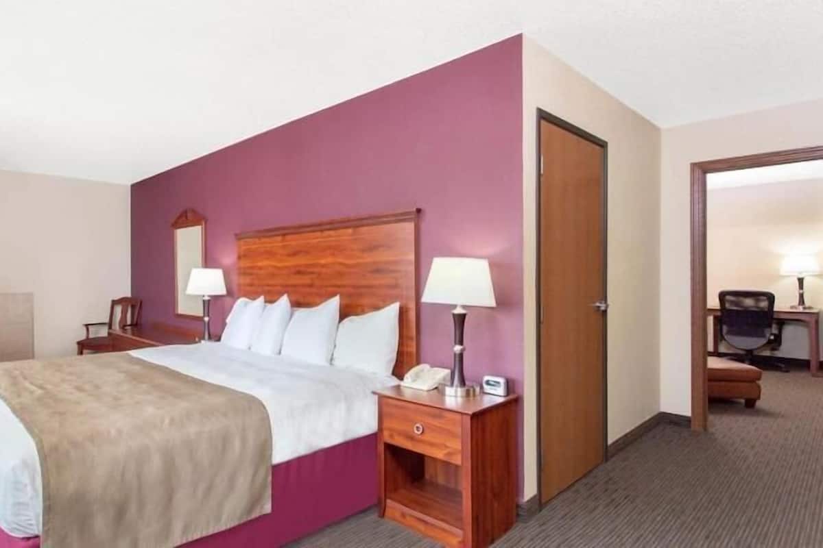 Een hotelkamer met een bed, twee nachtkastjes, een bureau, een stoel en een deur.