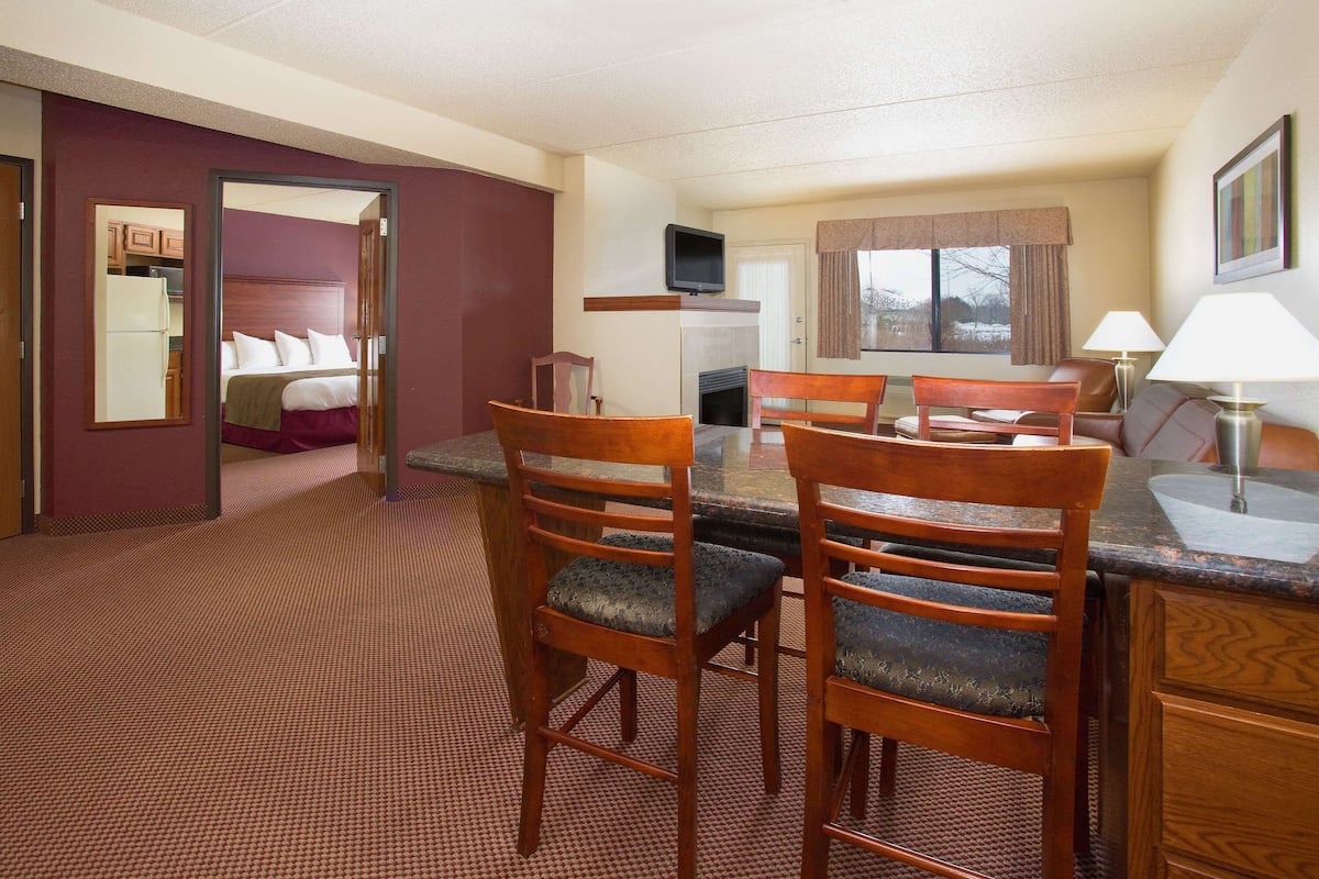 Een hotelkamer met een eethoek, een bed, een televisie en een open haard.