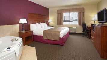 A hotel room with a large bed, a desk, a chair, a television, and a bathroom with a bathtub.
